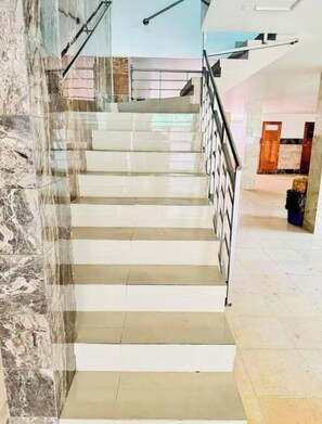 Una scala con una parete in marmo su un lato e una ringhiera in metallo.