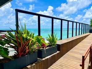 Eine Holzterrasse mit Pflanzkübeln und Blick auf den Ozean.