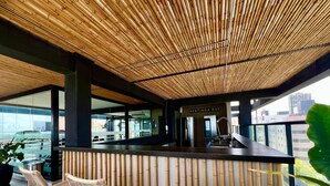 Uma área de bar com teto de bambu, balcão e cadeiras de vime.