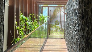 Uma escada de madeira que leva a um quarto com parede de pedra e portão de metal.