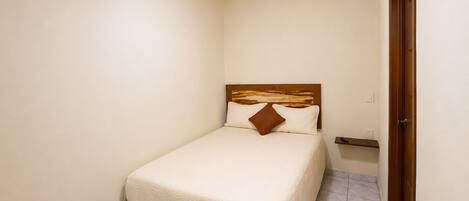 A bedroom with a bed, a ceiling fan, a wooden headboard, and a door.