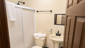 A bathroom with a toilet, sink, and shower.