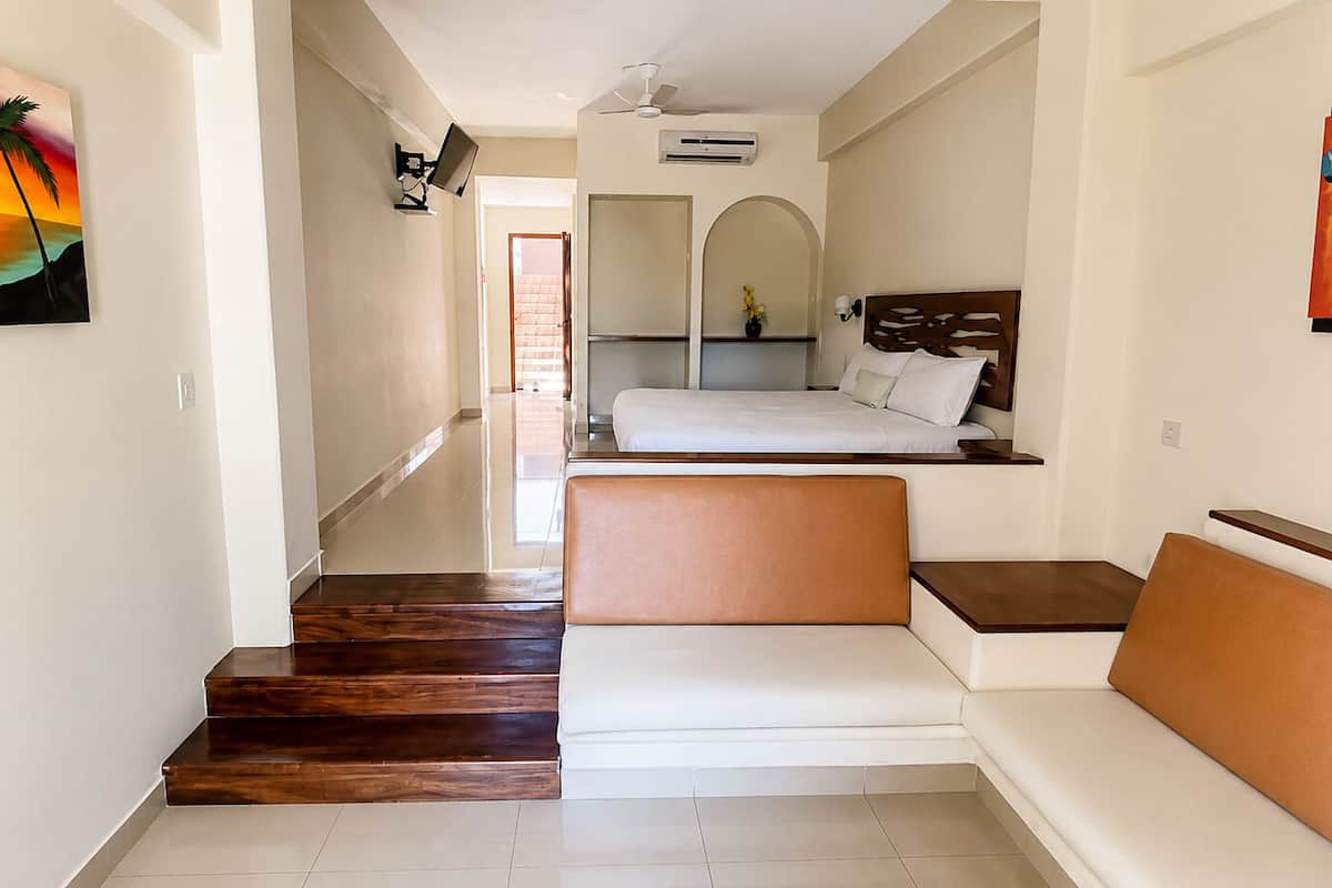 Una habitación de hotel con una escalera de madera, un sofá, una cama y un cuadro en la pared.