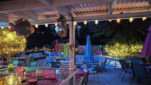 An outdoor patio with seating, a pool, and string lights.
