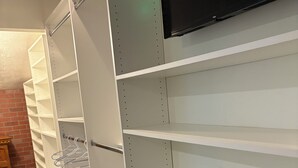 Een kamer met witte schapenkasten, een flatscreen televisie aan de muur en een bakstenen achtergrond.