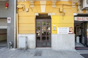 Ein Gebäude mit gelber Fassade, einer braunen Tür und einem Schild mit 'Bar S'.