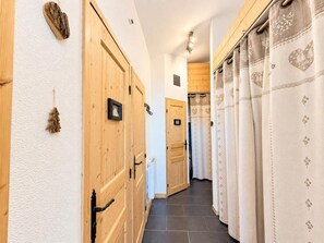 A hallway with wooden doors and a curtain with a floral pattern. - 10m from ski slopes, 4th floor, view valley, balcony, tv, ski locker, 24m², Les Menuires (Les Menuires)