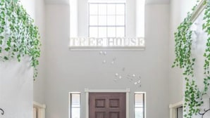 Un pasillo con una puerta de madera oscura, dos ventanas a cada lado y una alfombra con textura.