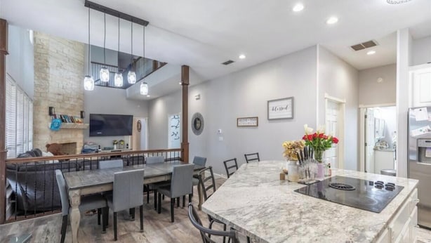 Una cocina moderna con encimera de mármol, estufa integrada y comedor con sillas y mesa.