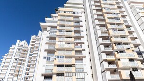 A high-rise residential building with multiple balconies, large windows, and a clear blue sky. - Sagan Brown Apartment, Armação de Pêra, Algarve (Armação de Pêra)