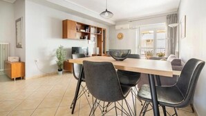 A modern kitchen with a dining table, chairs, and a hanging light fixture. - Casa Athenia Inn (Athina)
