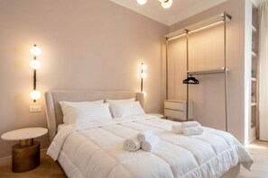 Ein Schlafzimmer mit Bett, Nachttischen, einem Kleiderschrank und Wandleuchten.