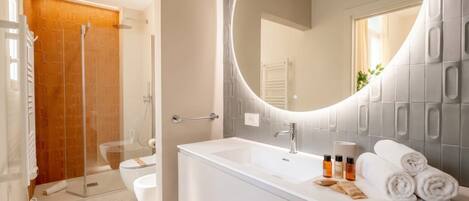A modern bathroom with a shower, toilet, and sink.