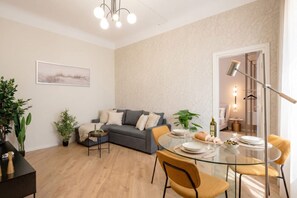Ein modernes Wohnzimmer mit einer Couch, einem Esstisch, Stühlen und einer Kronleuchter.