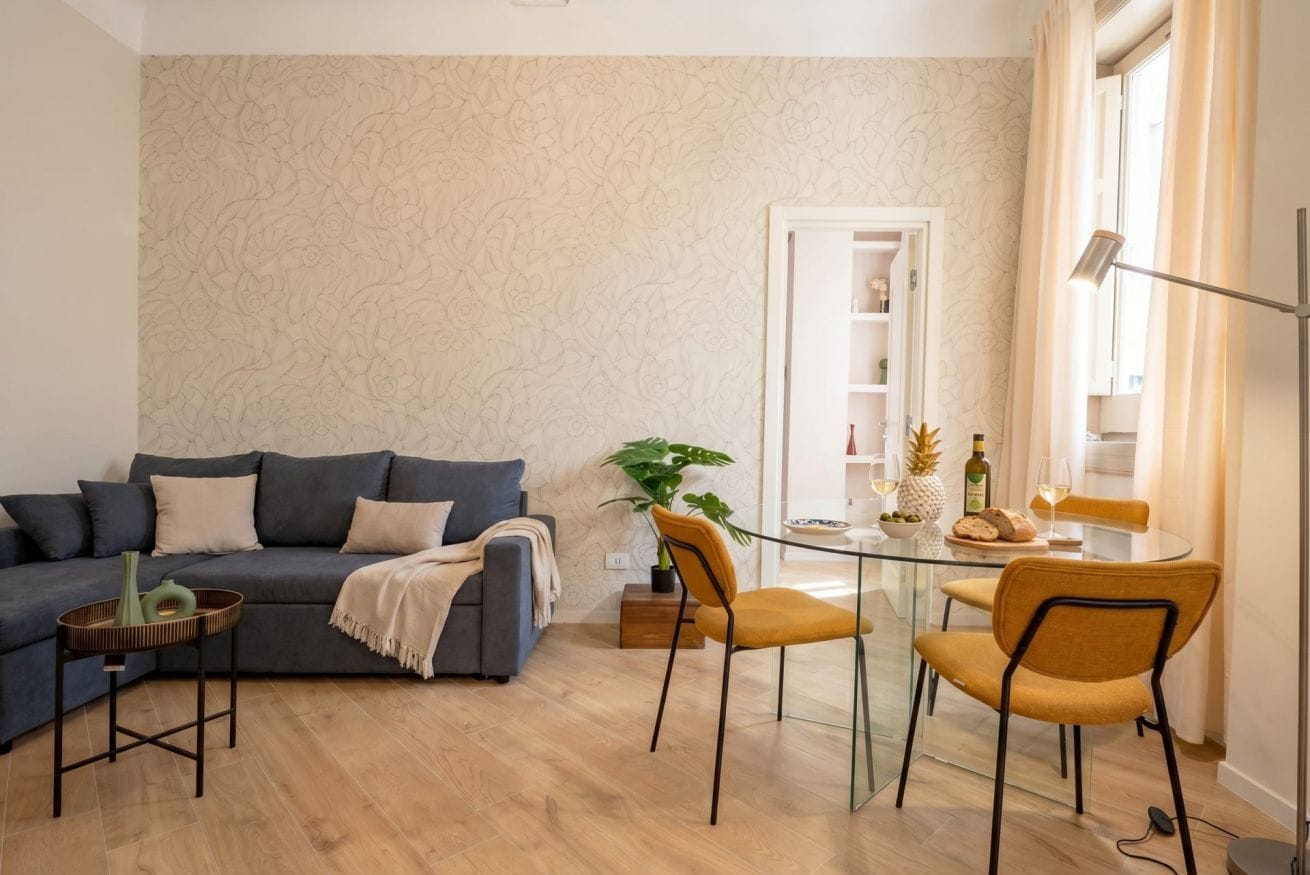 A modern living room with a sofa, a glass dining table, and chairs.