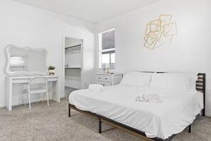 A bedroom with a bed, a desk, a chair, a wardrobe, and a window with blinds. - Spacious Group Stay w/ Dual Kitchens (Bakersfield)
