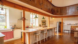 Una cocina amplia con vigas de madera, una isla central con taburetes de bar y vistas al exterior.