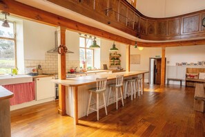 Een ruime keuken met houten balken, een centraal kookeiland met barkrukken, en uitzicht op de omgeving.