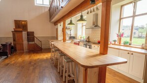 Una cocina con barra de madera, taburetes y vistas al exterior.