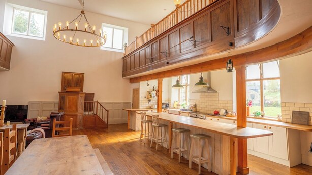 Una cocina amplia con techo alto, taburetes de madera y una isla grande.