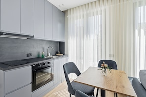 Una cocina moderna con armarios grises, una estufa negra y una mesa de comedor de madera con sillas.