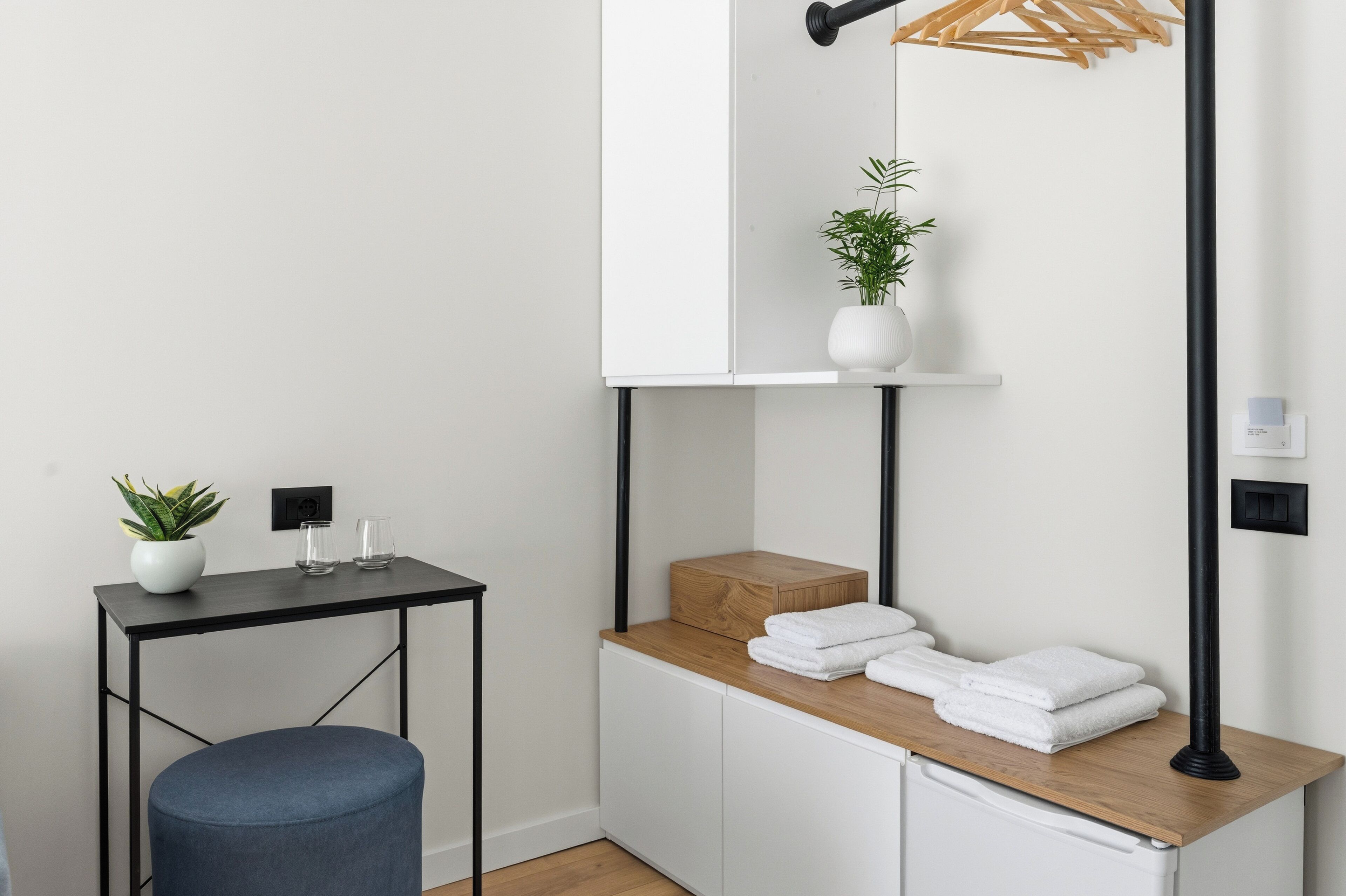 Een badkamer met een houten wastafelmeubel, een spiegel, een kamerplant en een handdoekrek.