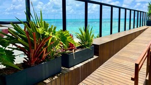 A wooden deck with planters and a view of the ocean. - Restinga 11 · Beachfront apartment in Caribessa with private balcony (João Pessoa)