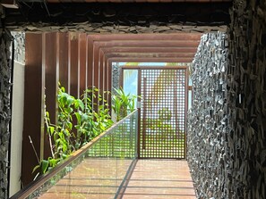 Eine Holztreppe führt zu einem Raum mit einer Steinwand und einem Metallgitter.