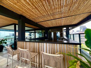 Eine Bar mit Bambusdecke, einer Theke und Korbstühlen.