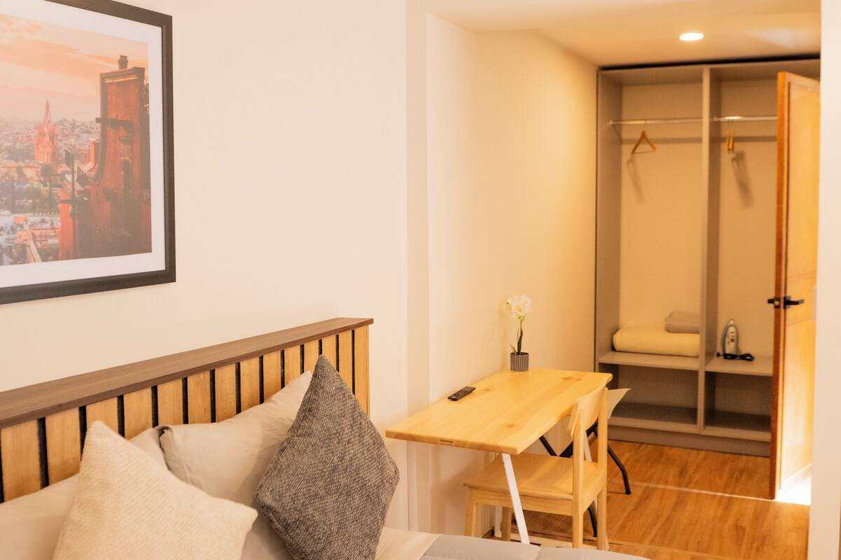Un dormitorio con cama, escritorio y vestidor.