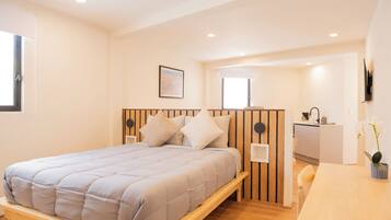 A bedroom with a bed, bedside table, and a small desk area.