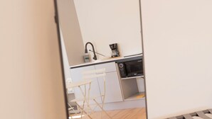 Cozinha moderna com micro-ondas, máquina de café e bancada branca.
