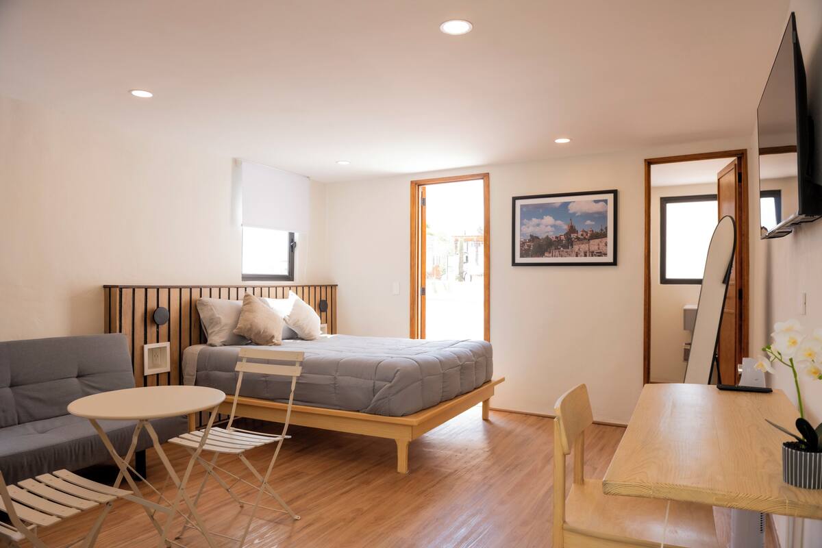 Un dormitorio moderno con cama, sofá, una mesita y un escritorio.