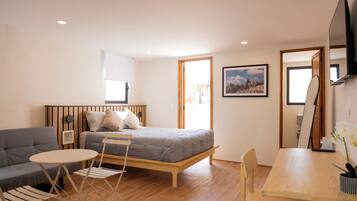 Un dormitorio moderno con cama, sofá, una mesita y un escritorio.