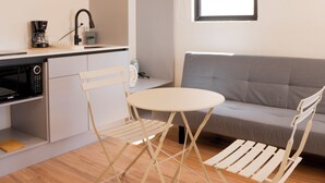 Espaço compacto com cozinha compacta, mesa de jantar com cadeiras, sofá e janela que proporciona iluminação natural.