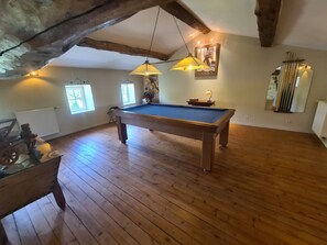 A pool table in a room with wooden floors, a ceiling with exposed beams, and a window with natural light. - Longère charentaise 10 persons near SAINTES, ROCHEFORT ? OLERON ISLAND (Sainte-Radegonde)
