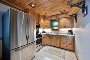 Eine Küche mit Holzschränken, Edelstahlgeräten und einem gemusterten Teppich.