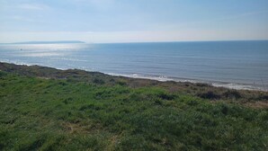 A coastal landscape with a grassy foreground and a view of the sea. - Seaside Retreat in New Milton, up to 6 Guests (New Milton)