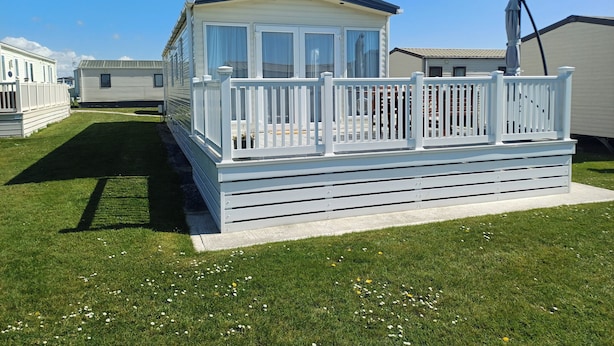 A caravan with a white deck and a 'Carnaby' sign, surrounded by other caravans. - Seaside Retreat in New Milton, up to 6 Guests (New Milton)