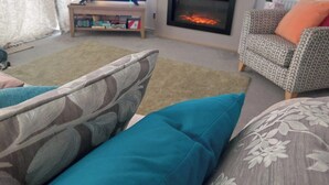 A living room with a television, fireplace, patterned sofa, and a rug. - Seaside Retreat in New Milton, up to 6 Guests (New Milton)