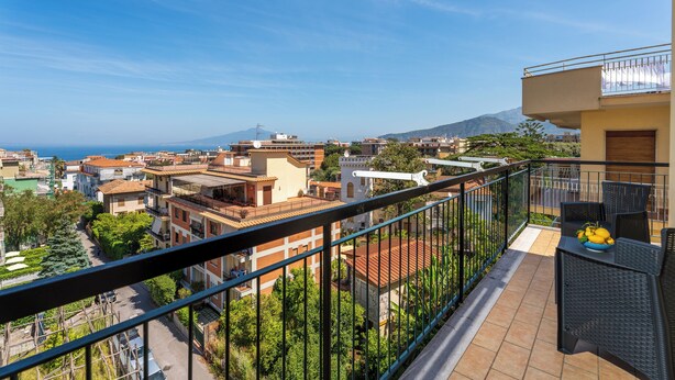 A balcony with a view of a cityscape, including buildings and a mountain in the distance. - YourHome - Nerea & Nicea Apartments (Sorrento)