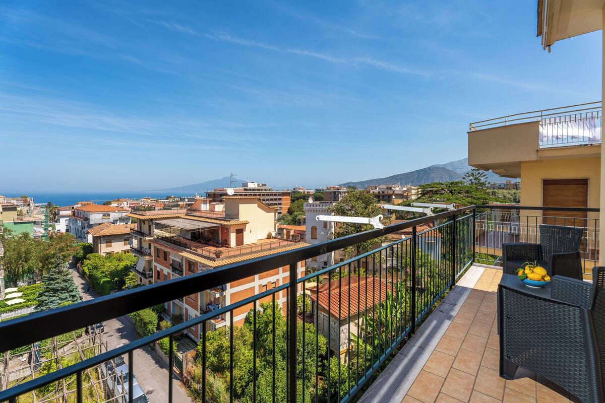 A balcony with a view of a cityscape, including buildings and a mountain in the distance.