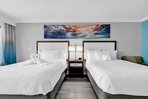 A hotel room with two beds, a nightstand, a wall-mounted artwork, and a view of the ocean. - Grand Cayman Resort 138 (Myrtle Beach)