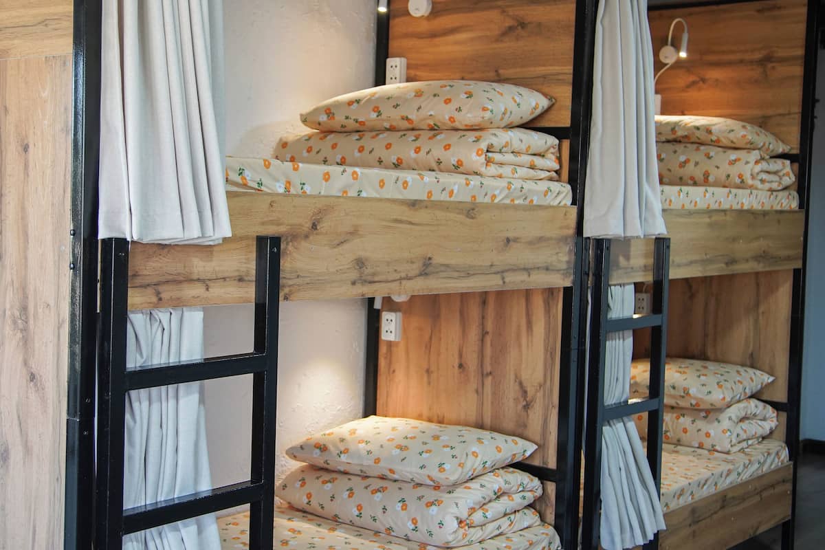 Een stapelbed met bloemenbedrukking, een houten hoofdbord en een wandlamp.