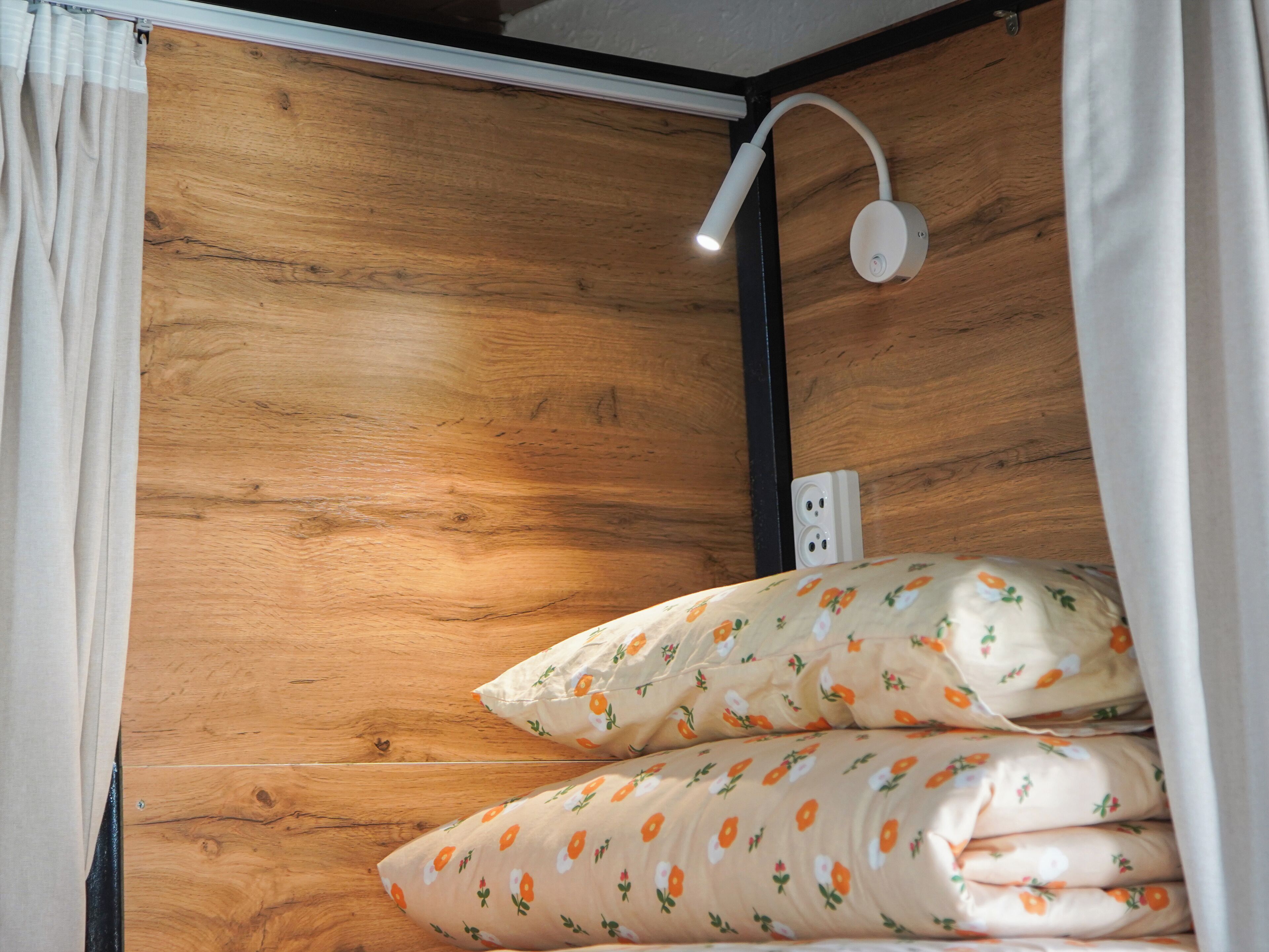 A wooden wall with a white electrical outlet and a white wall-mounted light fixture.