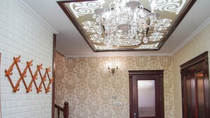A hallway with patterned wallpaper, a wooden door, a chandelier, and a wall-mounted light fixture. - Dolon Hostel (Bishkek)