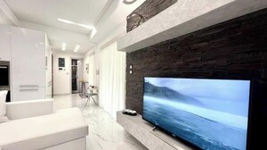 Una sala de estar moderna con un televisor de pantalla plana grande, un sofá blanco y un piso de mármol.