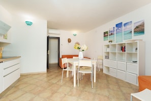 Un comedor con una mesa y sillas, una estantería y una pared decorada con cuadros.