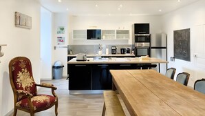 Una cocina moderna con una mesa y sillas de madera, un cubo de basura y una pizarra con escritura.