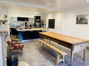 Uma cozinha moderna com mesa e banco de madeira, geladeira preta e cafeteira.